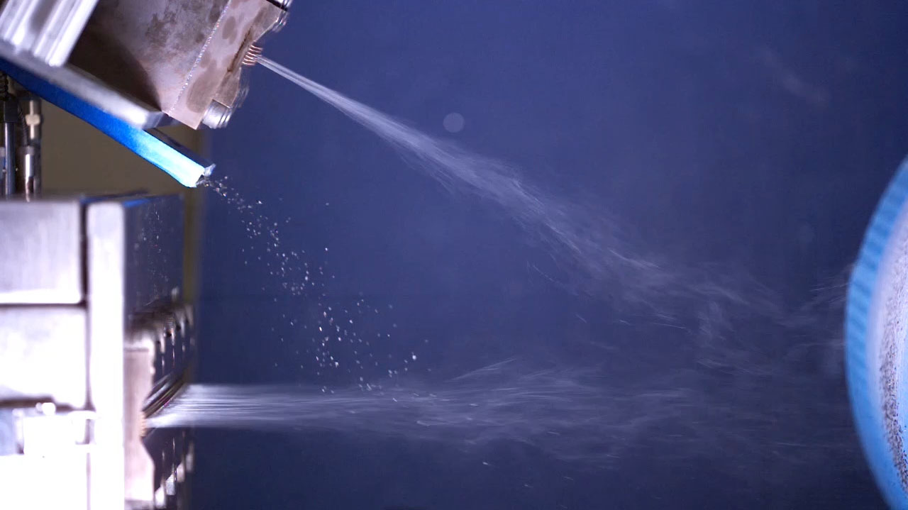 Close-up visual of dual-beam meltblown process with particle dispersion.
