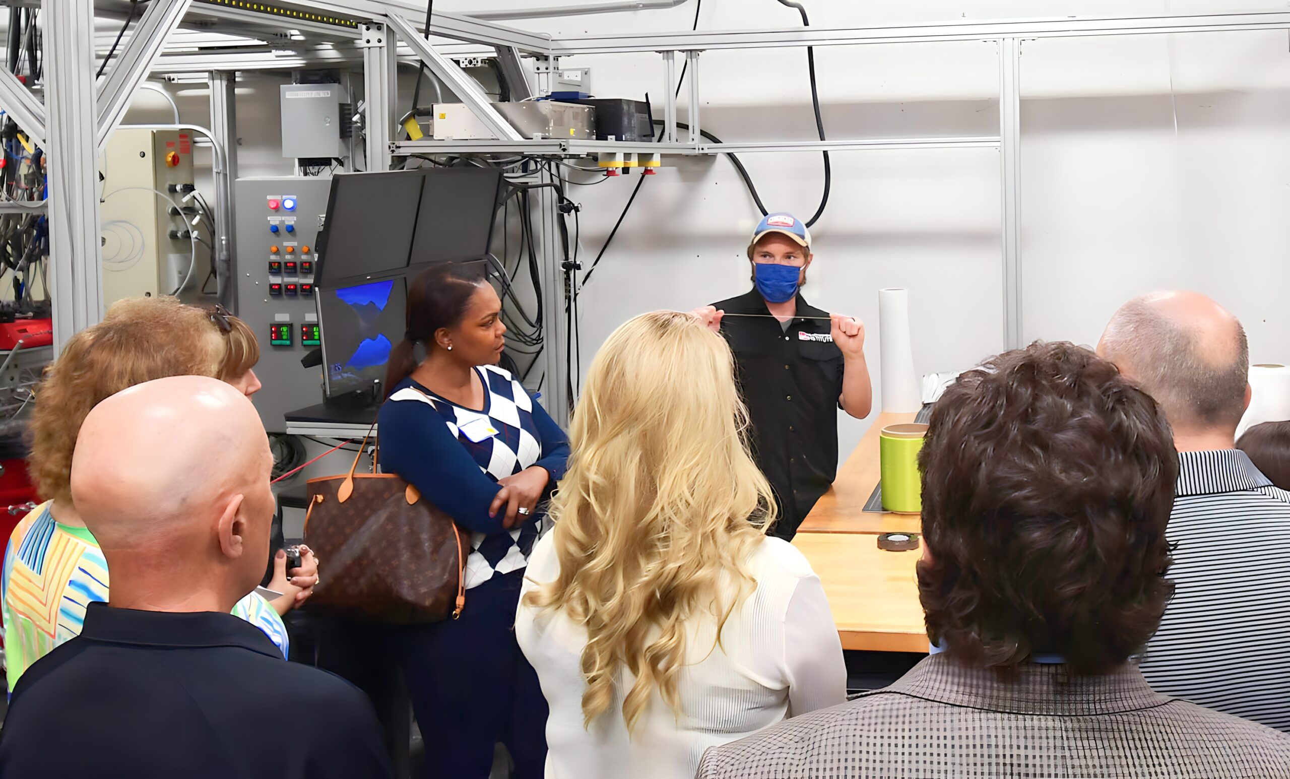 Fiber and Polymer Science Lab Manager Eric Lawrence demonstrates the elasticity characteristics of a fiber for a tour group.